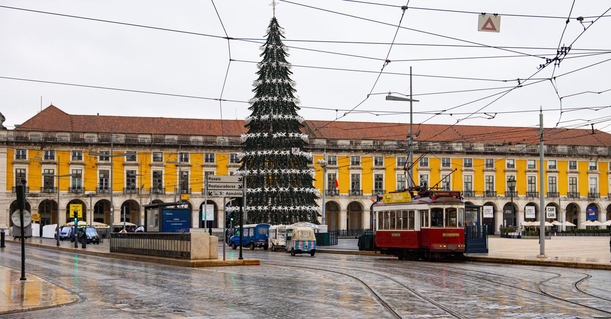 Tram in Lisbon's historic square with a festive Christmas tree and colonial architecture.