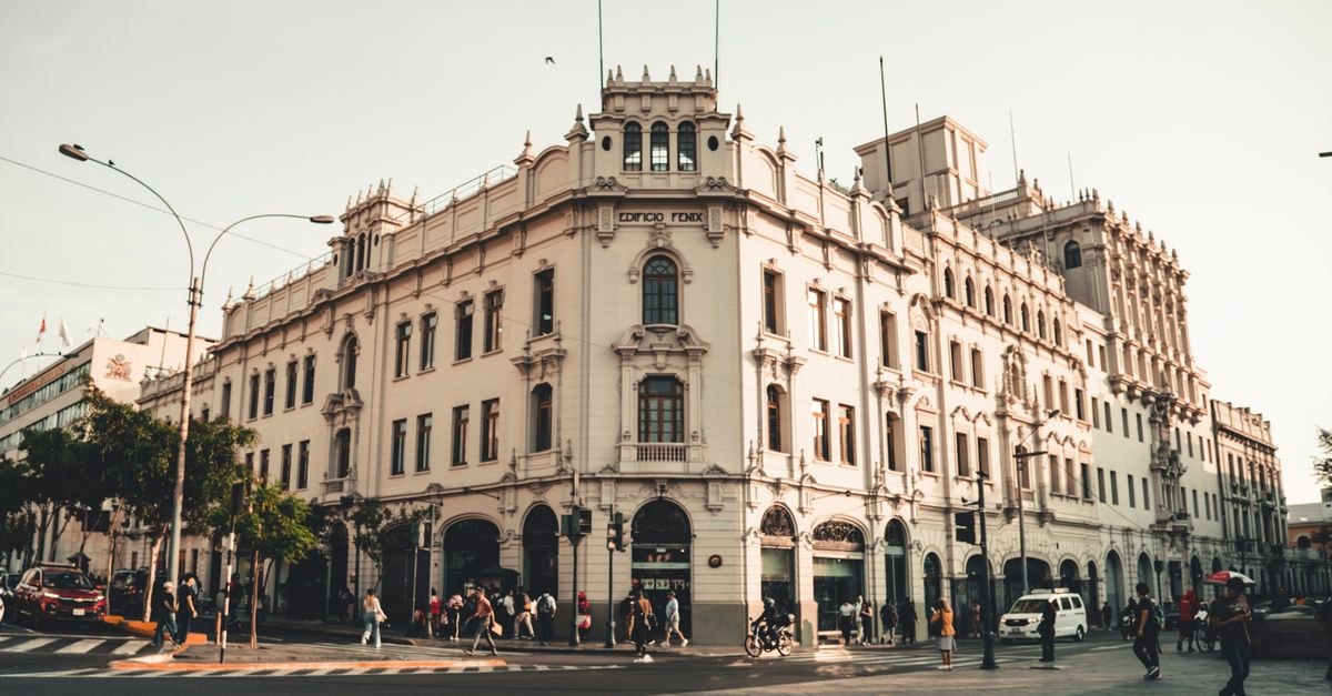 Historic Edificio Fenix with pedestrians in a bustling city street at sunset, showcasing classical architecture.
