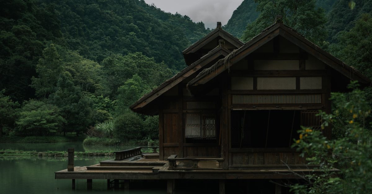 Bijie Travel Guide: A Quiet Guizhou Escape Into Highland Air Tranquil wooden pavilion by a lake surrounded by lush greenery in Guizhou, China.