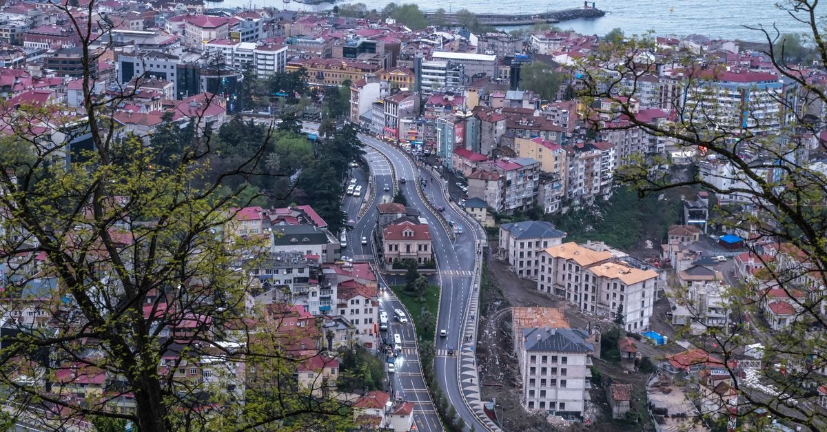 Sassy in Pikine: A Pocket-Size Stay Near Stade Alassane Djigo Breathtaking aerial view of a coastal city with winding roads, framed by trees at dusk.