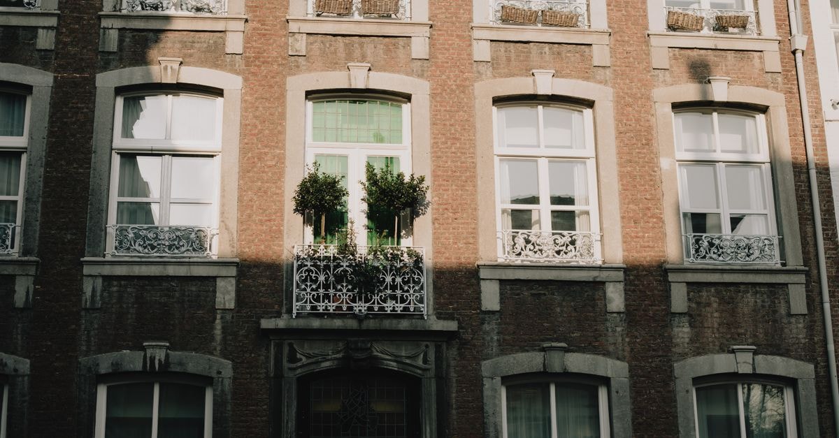 Elegant Maastricht building facade with intricate ironwork and lush greenery under natural light.