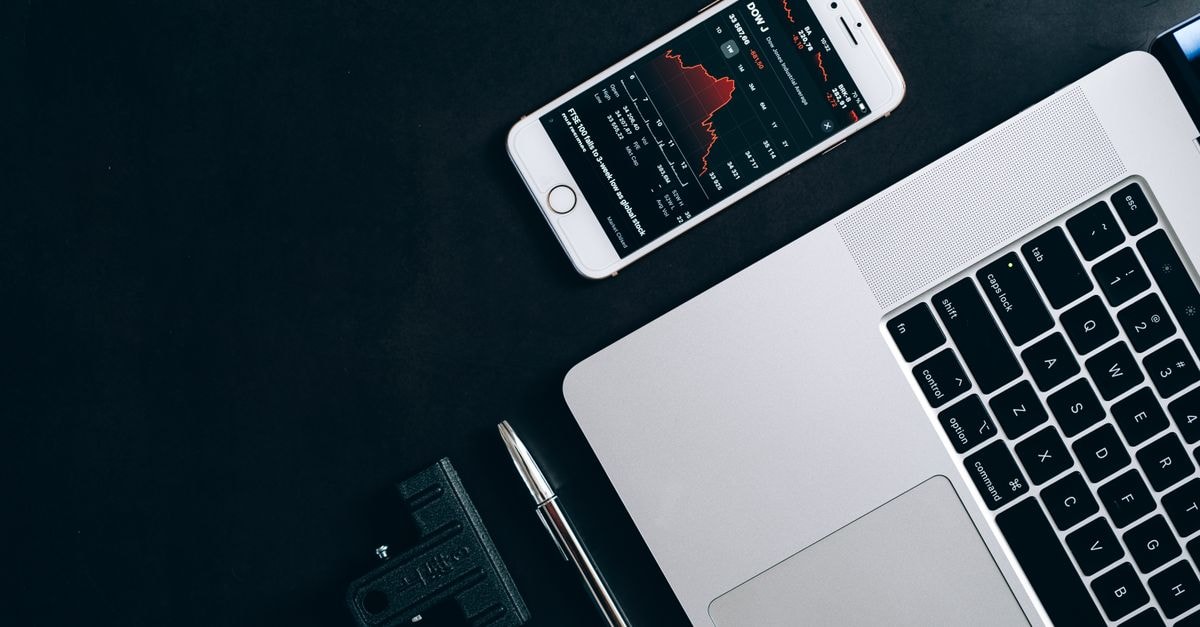Modern workstation setup showcasing laptop, smartphone, and financial data for business use.