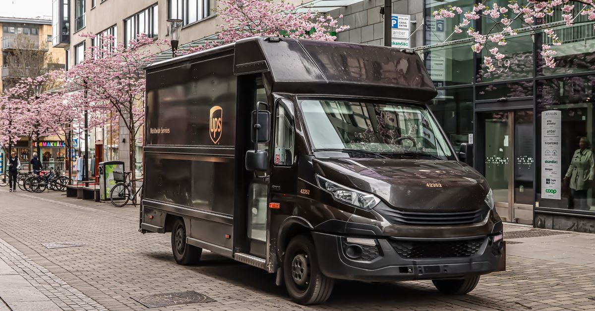 Black UPS delivery truck parked on a street in Jönköping, Sweden with cherry blossoms in spring.