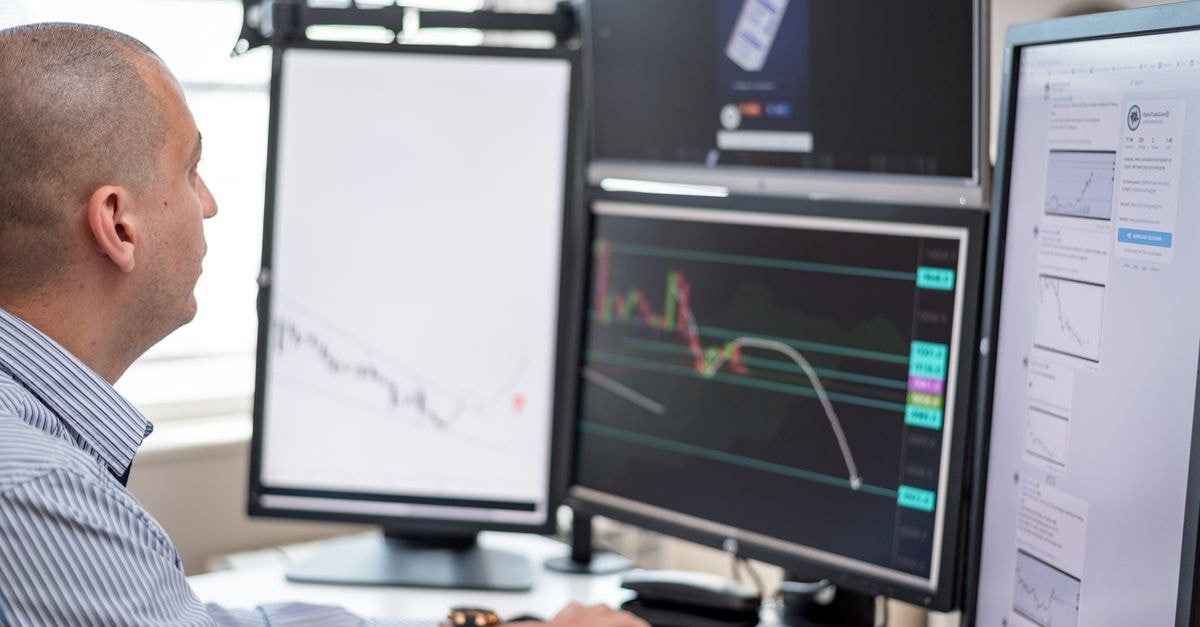 Analysts split on Shopify stock after sell-off pushes shares below 200-day moving average Stock trader analyzing financial graphs on multiple computer monitors in an office setting.
