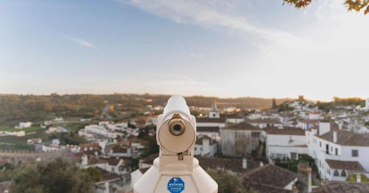 Hotel Villa Batalha in Leiria: A Monastery-View Retreat Telescope overlooking the charming rooftops and landscape of Óbidos, Portugal during daytime.