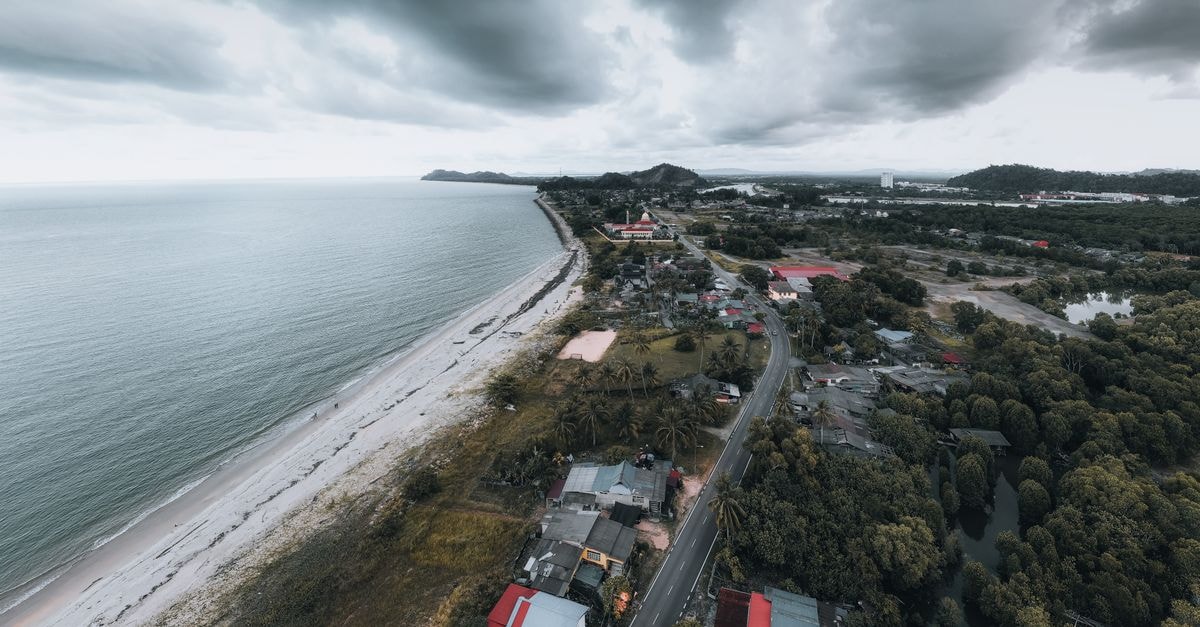 Imperial Hotel, Miri: A One-Stop Stay Inside the Golden Triangle Aerial view of a coastal town with a beach under cloudy skies, capturing the natural landscape and ocean.
