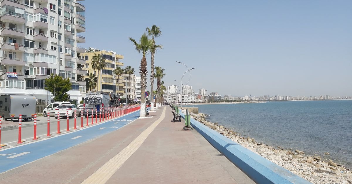 A scenic view of the Mersin coastline with palm trees and modern buildings.
