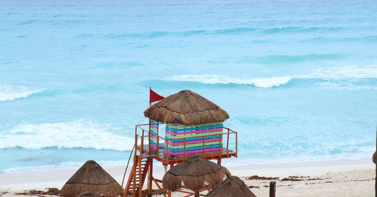 Posada BOMBAY, Cancún: A Practical Stay on Calle 10 Poniente Vibrant lifeguard tower on Cancún's sandy beach, set against turquoise ocean waves.