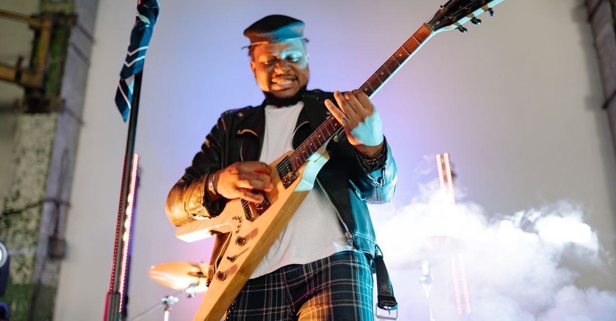 Vibrant live performance of a guitarist in action with smoke effect on stage.