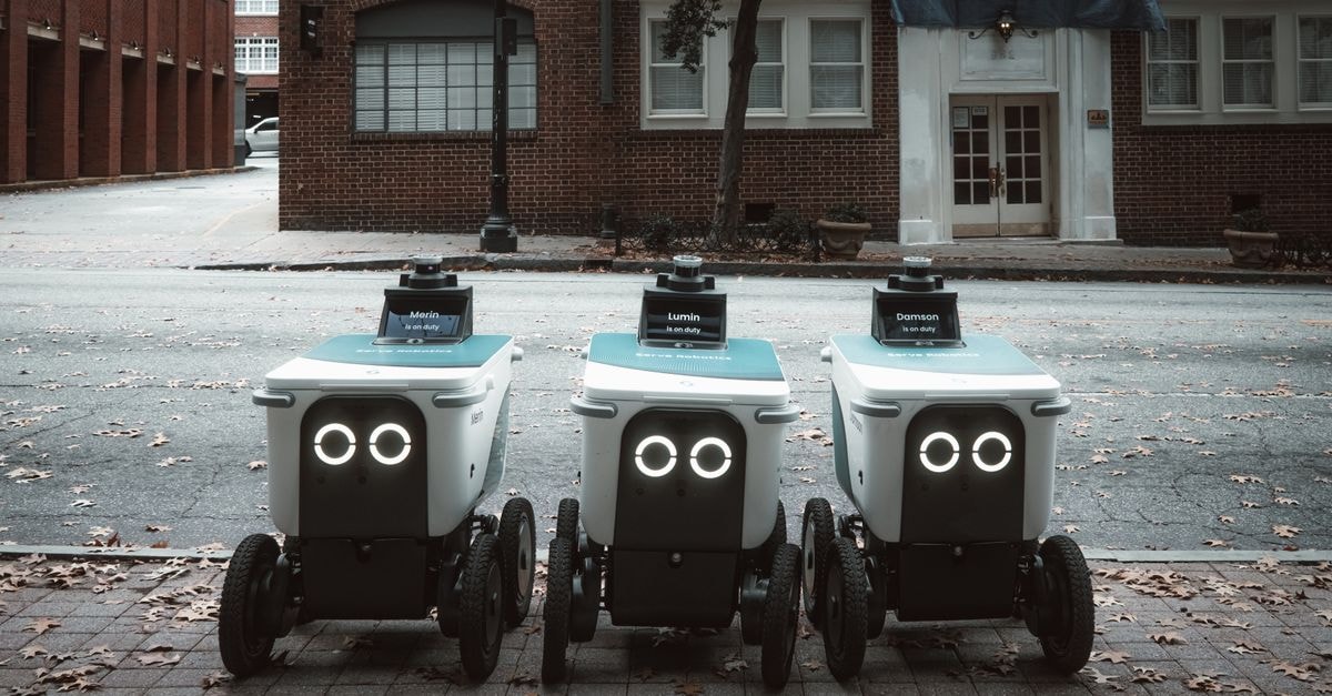 Anthropic reports AI models autonomously hacked three organizations in tests; U.S. lawmakers probe DoorDash over Chinese AI model use Autonomous delivery robots positioned on an urban street, showcasing technology in modern logistics.