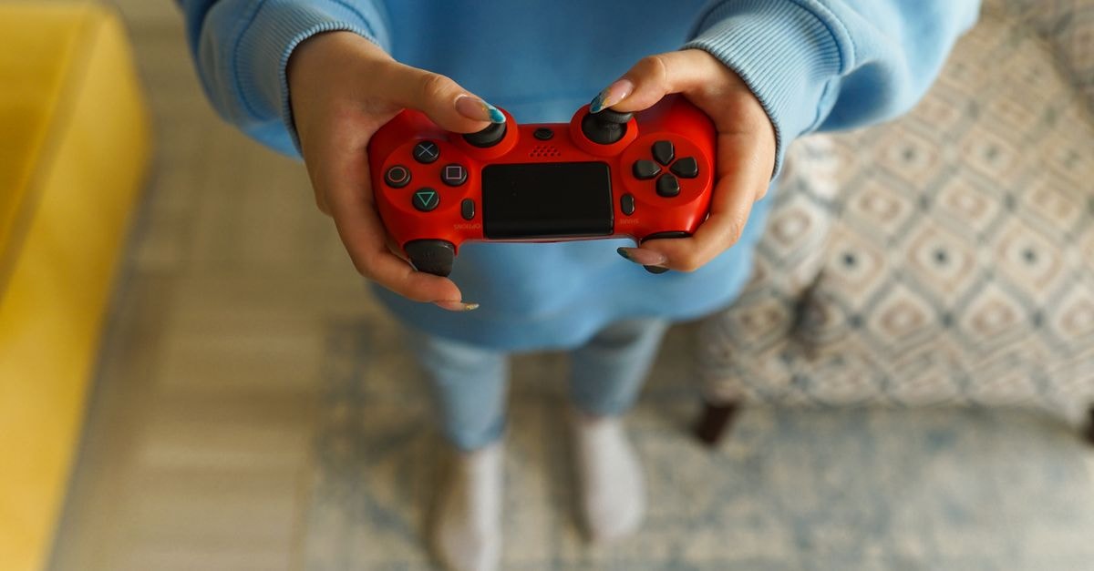 Pokémon Pokopia Crosses Five Million Units Sold on Nintendo Switch 2 Person holding a bright red gaming controller indoors, focusing on gameplay.