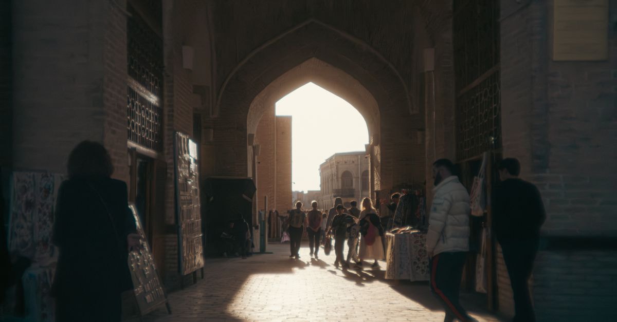 A bustling market scene in a historic archway, capturing daily life in Uzbekistan.