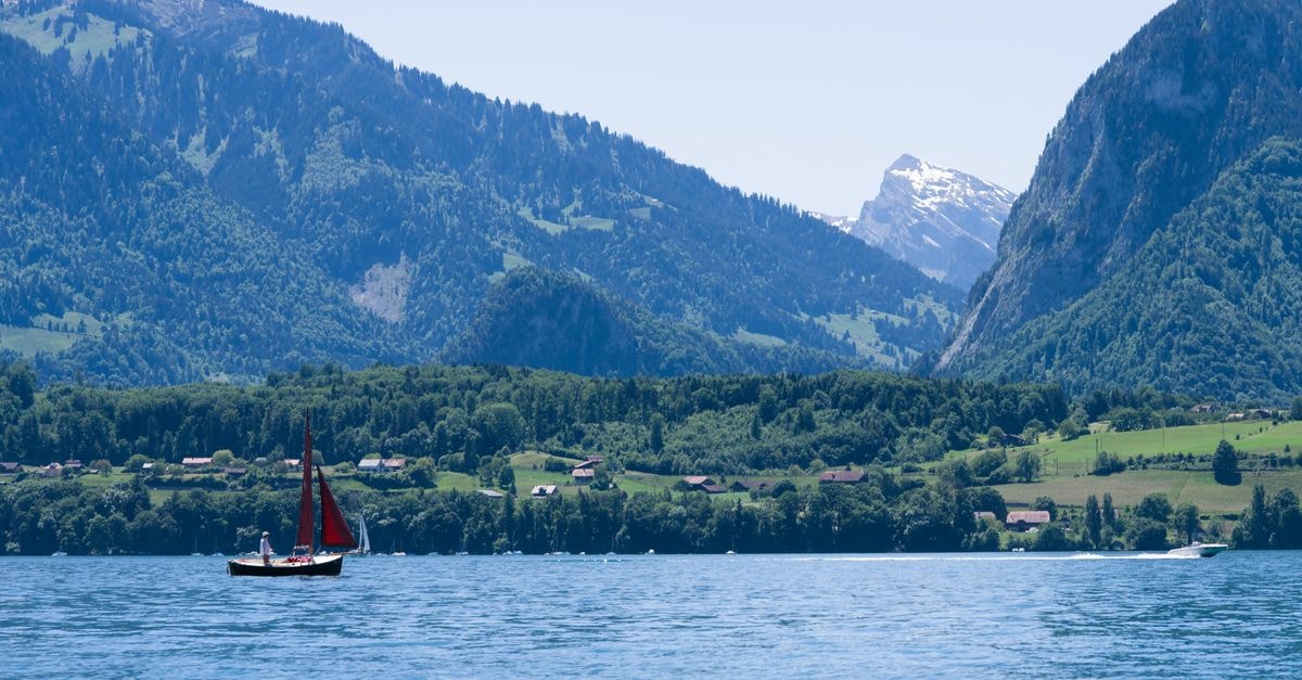 A picturesque sailboat on Lake Thun with the Swiss Alps in the background.