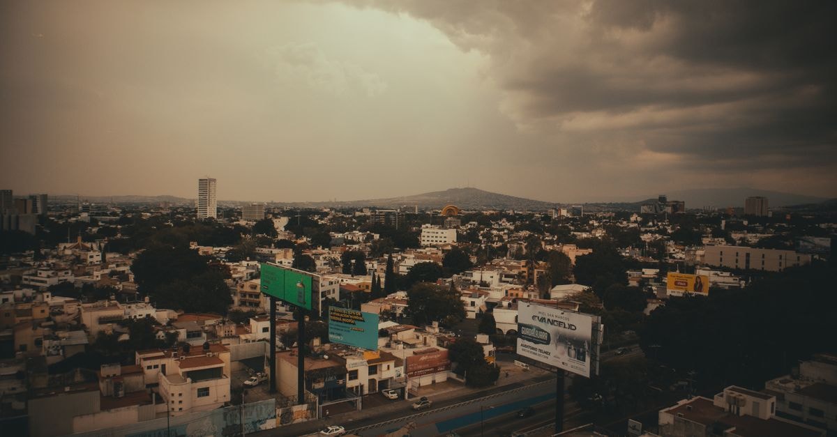 城市景觀鳥瞰圖，烏雲密佈籠罩上空，營造出戲劇化的都市氛圍。