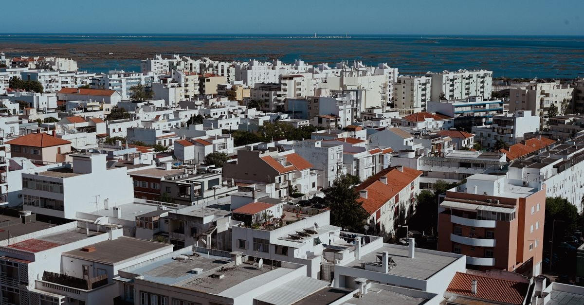 3HB Faro in Faro: Algarve-Inspired Sophistication in the Old Town Aerial view of Faro, Portugal cityscape with apartment buildings and ocean in the background.
