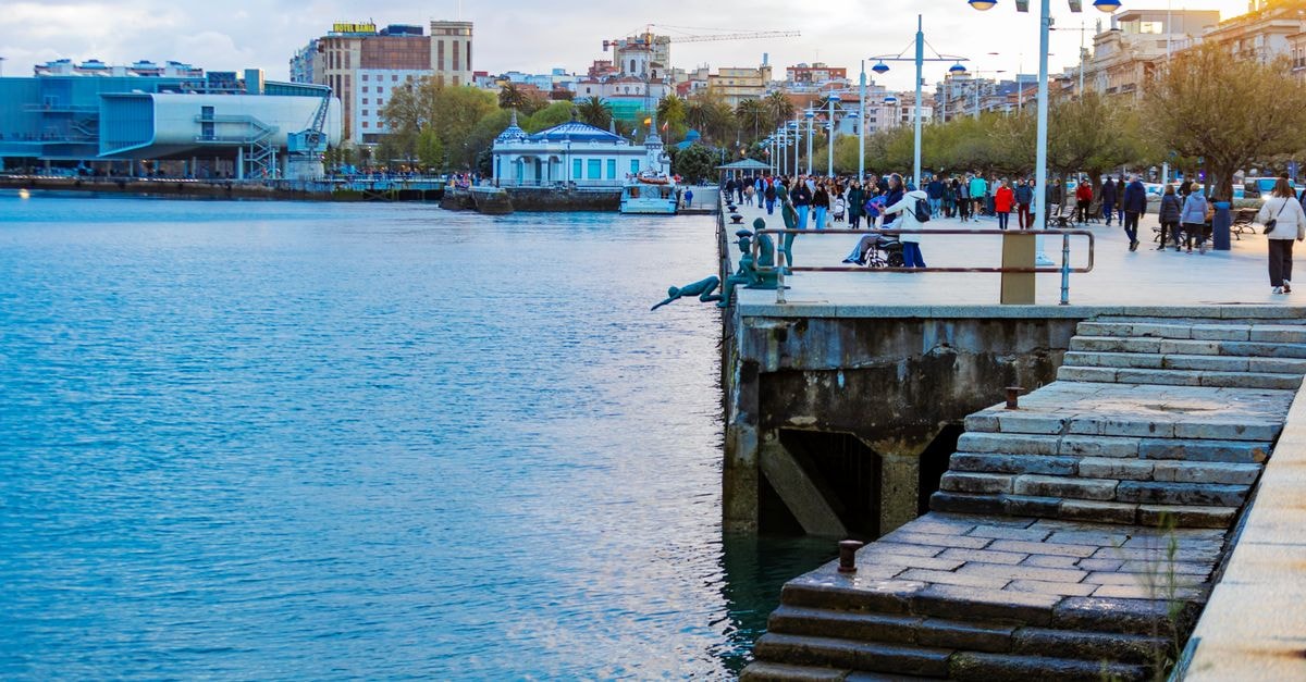 Lively waterfront scene with people enjoying the promenade by the sea at dusk.
