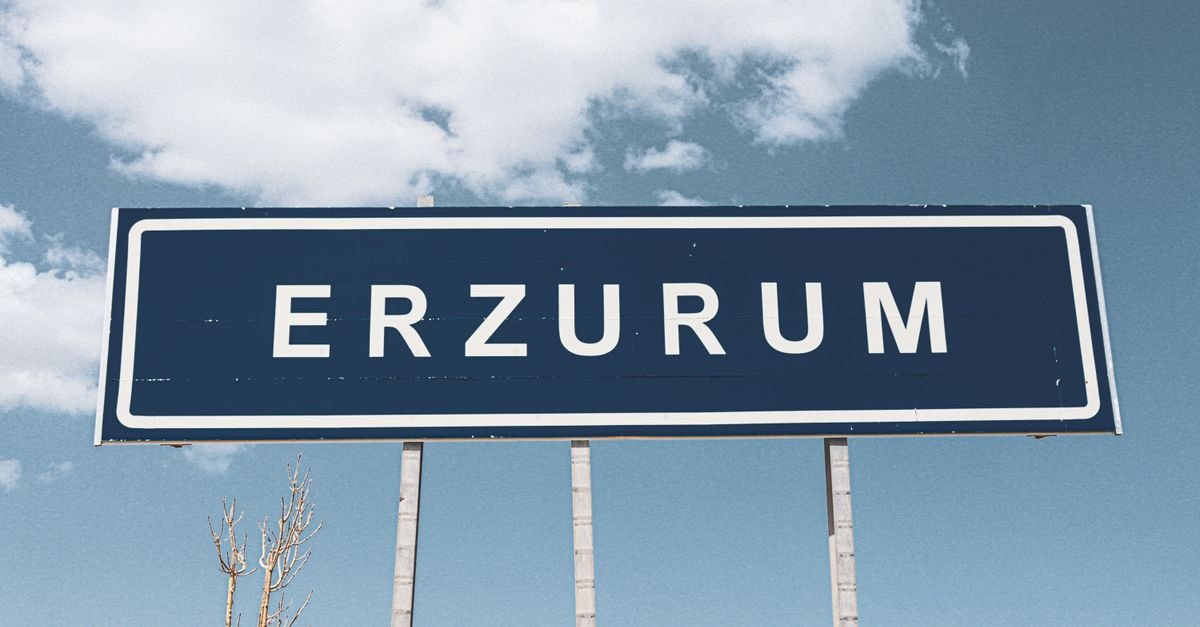 Street sign for Erzurum against a backdrop of a bright blue sky and fluffy clouds.