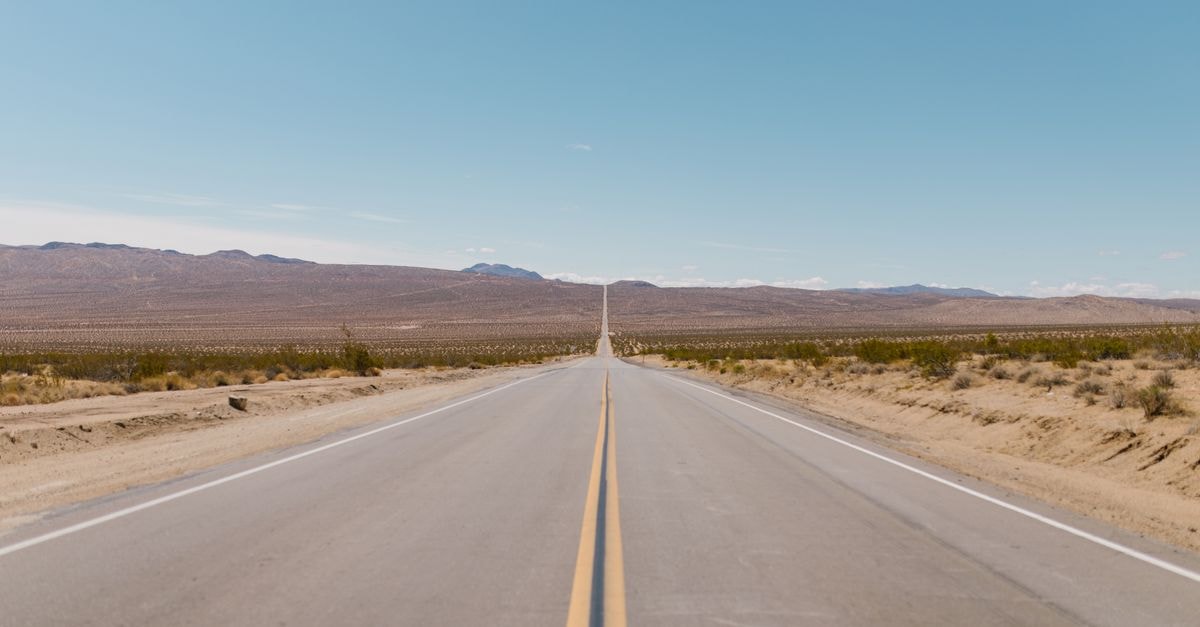 Semnan Travel Guide: History, Highways and Desert Horizons A long, straight road stretches through a vast desert landscape under a bright blue sky.