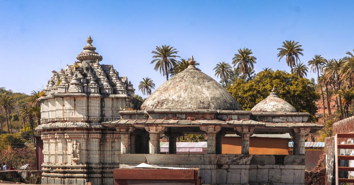 Discover the intricate architecture of an ancient temple in Gujarat, India, surrounded by palm trees.