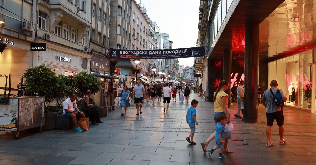 Lively scene with shops and pedestrians on Knez Mihailova Street in Belgrade during evening.