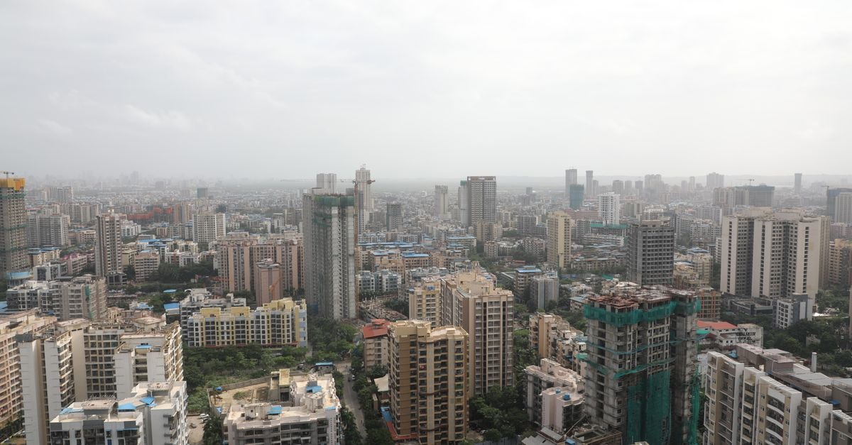 Overhead view of a bustling cityscape with high-rise buildings under a cloudy sky.