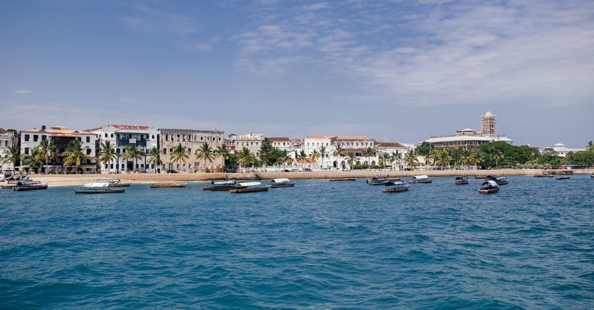 Merca Travel Guide: A Quiet Somali Port Town Worth Knowing Scenic view of boats and historic Stone Town, Zanzibar under a blue sky.
