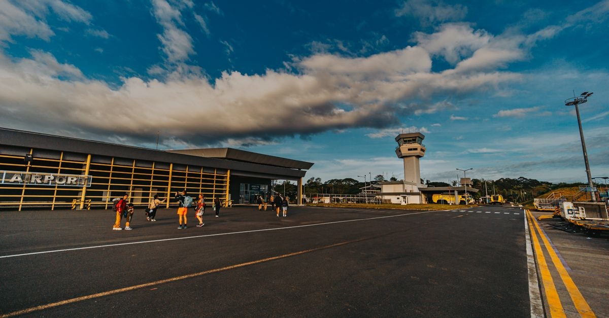 Caazapa Travel Guide: Planning Tips, Costs and Things to Do A small airport terminal with people walking on the tarmac under a blue sky.
