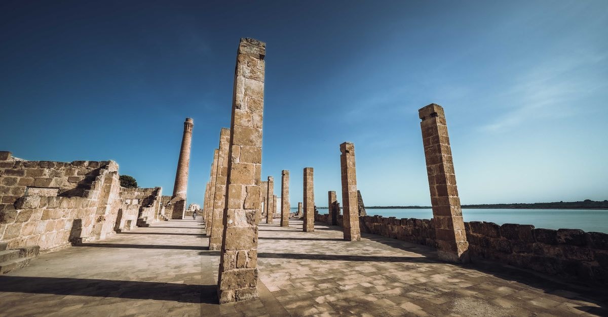 Tipasa Travel Guide: Mediterranean Ruins by the Sea Explore the ancient stone pillars of the Tonnara of Vendicari in Italy's nature reserve under a clear blue sky.