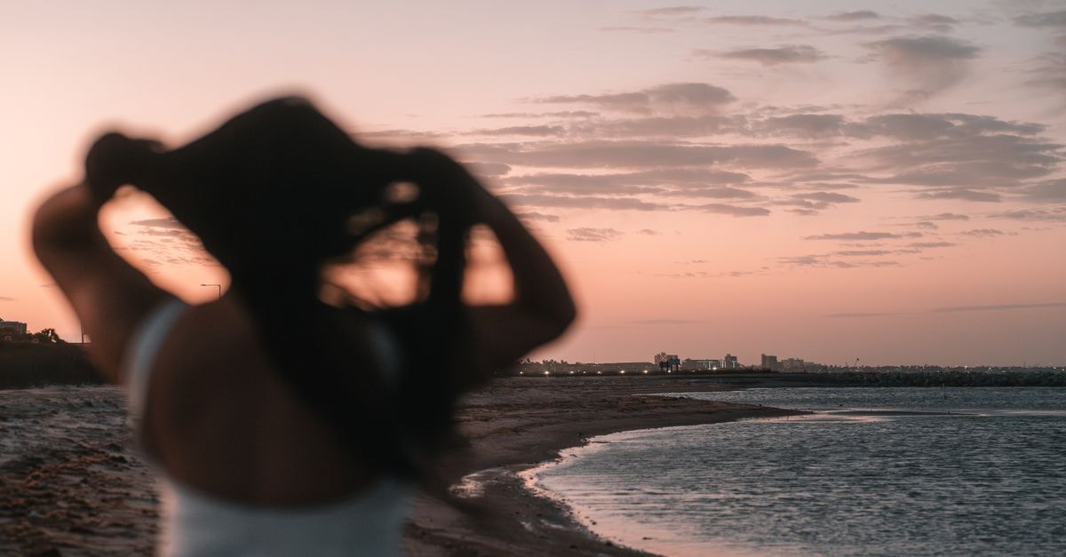 A silhouette of a woman at sunset on the peaceful shores of Corpus Christi, Texas.