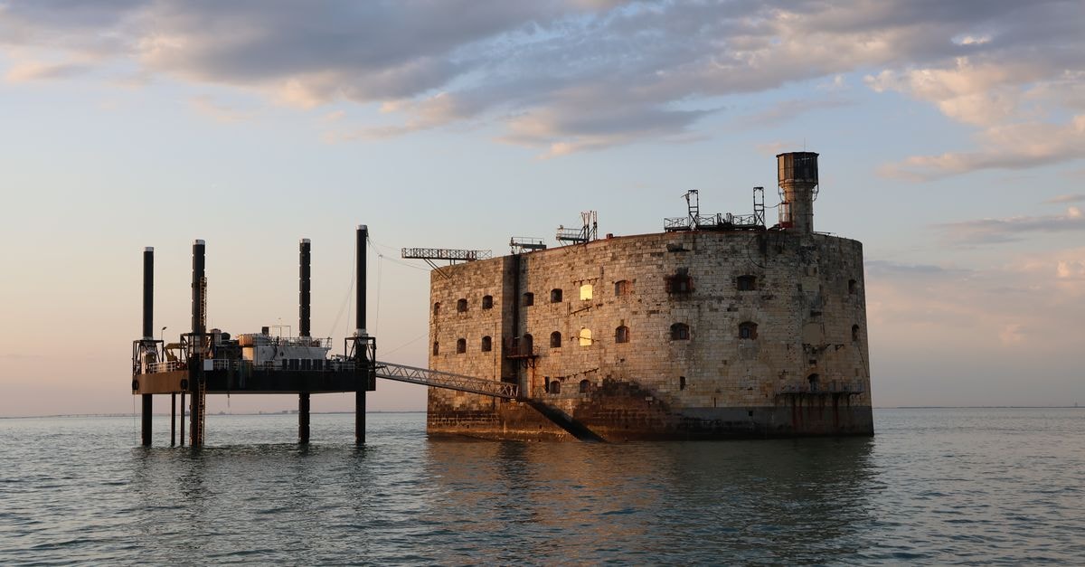 Captivating view of Fort Boyard illuminated by sunset colors over the tranquil sea.