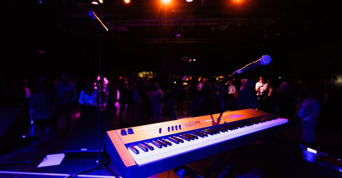 A vibrant nightclub scene with a keyboard and microphone on stage, ready for a live performance.