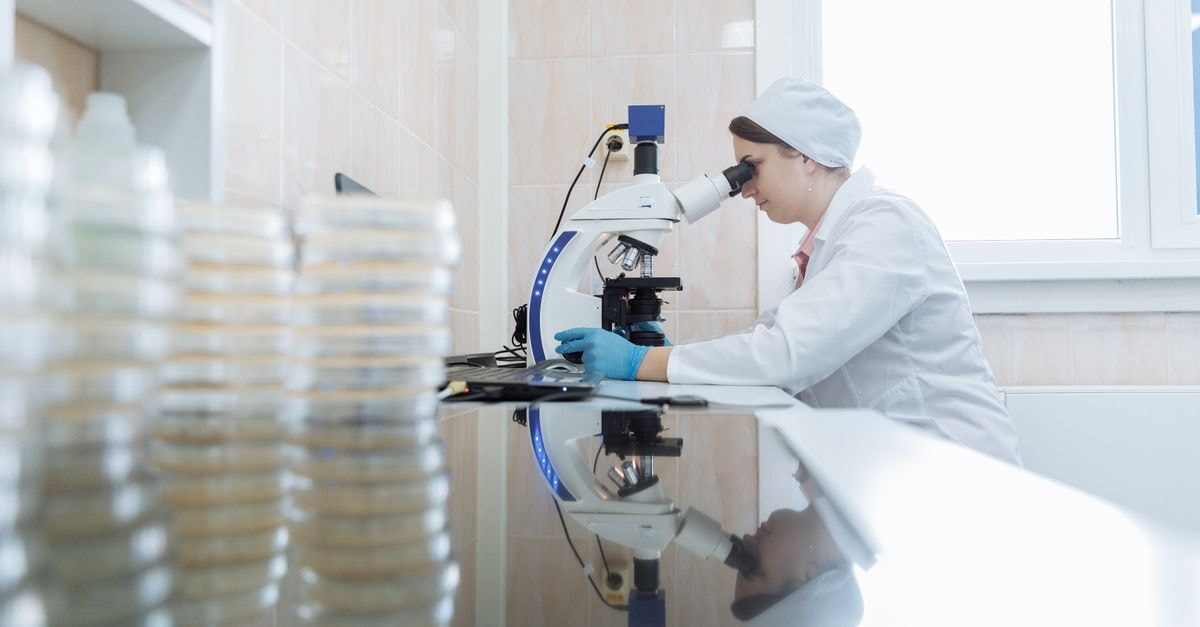 女性科學家在實驗室環境中使用顯微鏡，專注於研究。