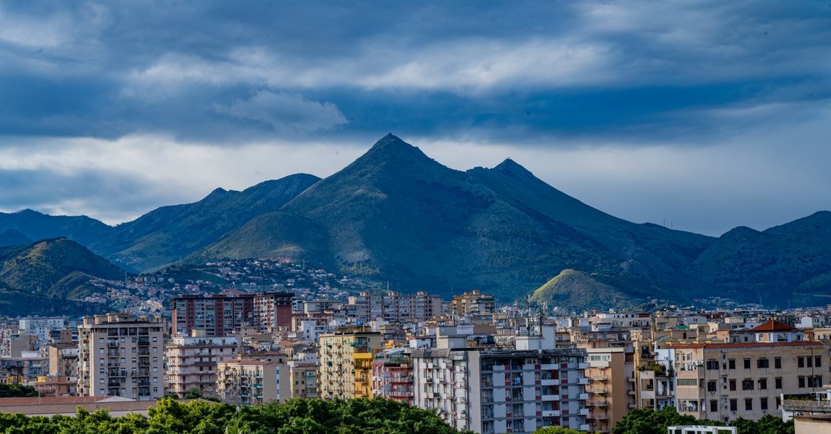 Eurostars Centrale Palace Hotel, Palermo — Heritage Stay Along Via Vittorio Emanuele View of Palermo cityscape with majestic mountainous backdrop under dramatic cloudy sky in Sicily, Italy.