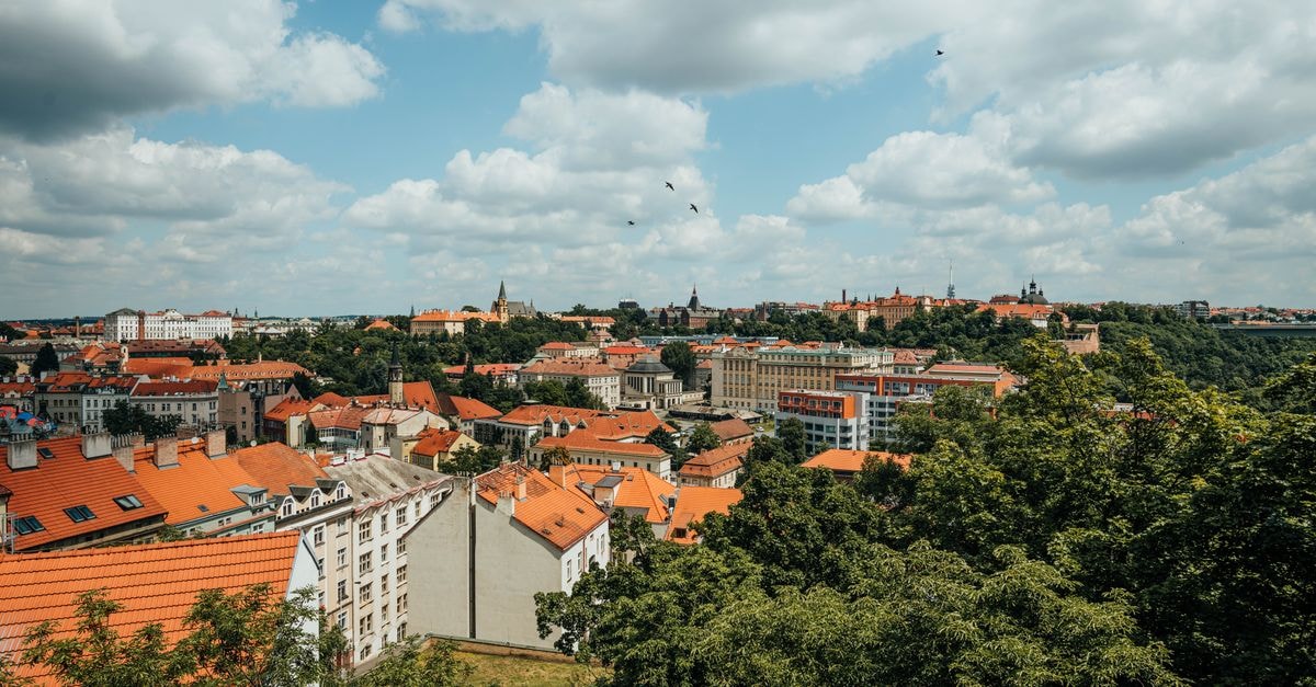 Focus Hotel Premium in Olsztyn: A Designer Stop Near the Old Town A beautiful panoramic view of a historic city with orange rooftops and lush greenery under a cloudy sky.