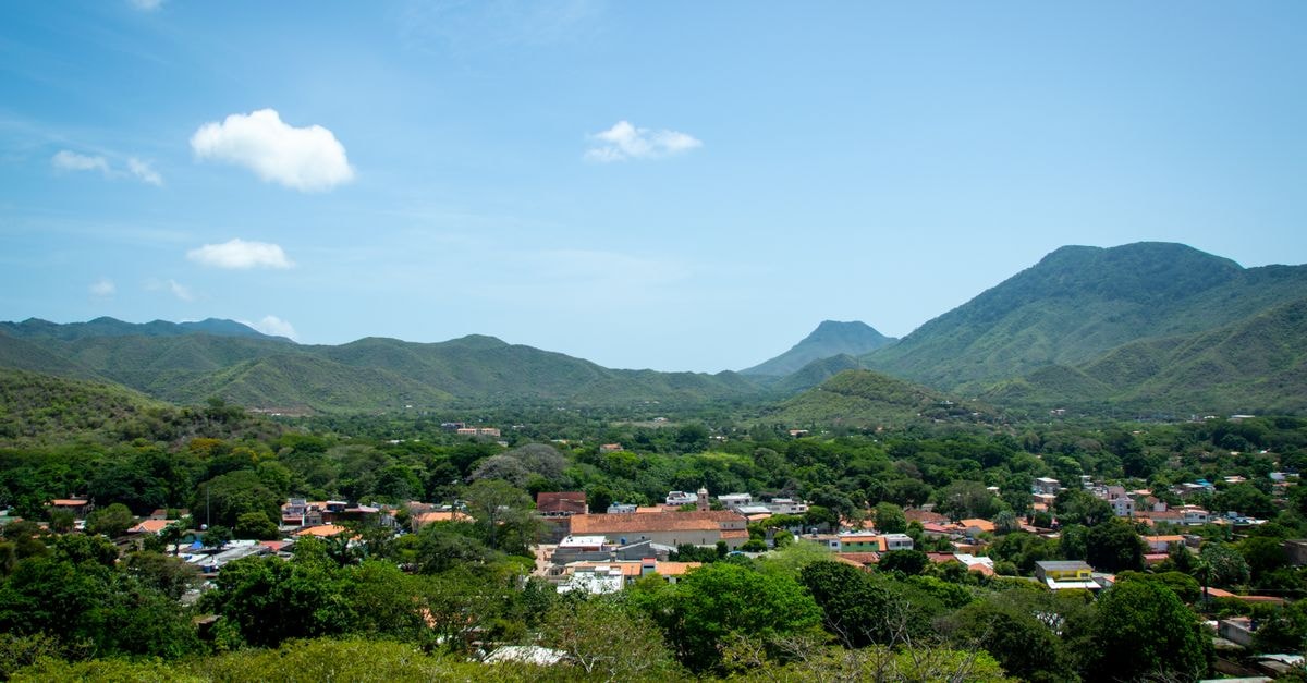 Picturesque aerial view of a village nestled among lush green hills and forests.