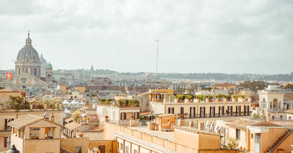 Roma Luxus Hotel in Rome: An 18th-Century Palace in Rione Monti Panoramic view of Rome's historic rooftops highlighting classic Italian architecture and St. Peter's Basilica.