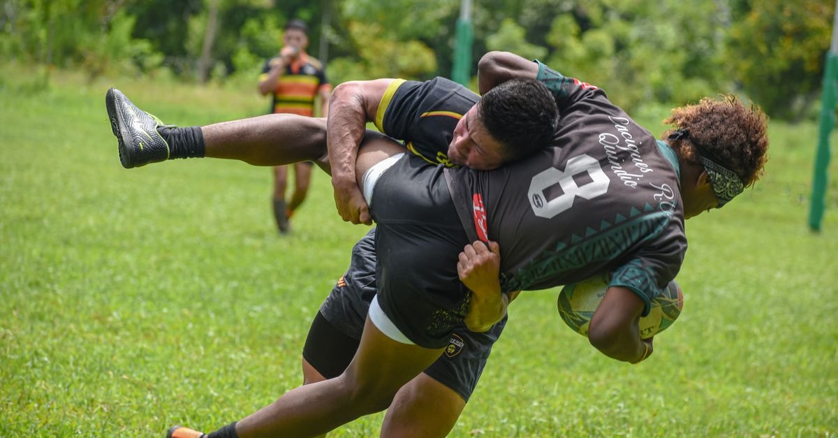 Fiji beats Canada 45-29 to reach Pacific Nations Cup final Rugby players in an action-packed tackle during a competitive outdoor match on a sunny day.