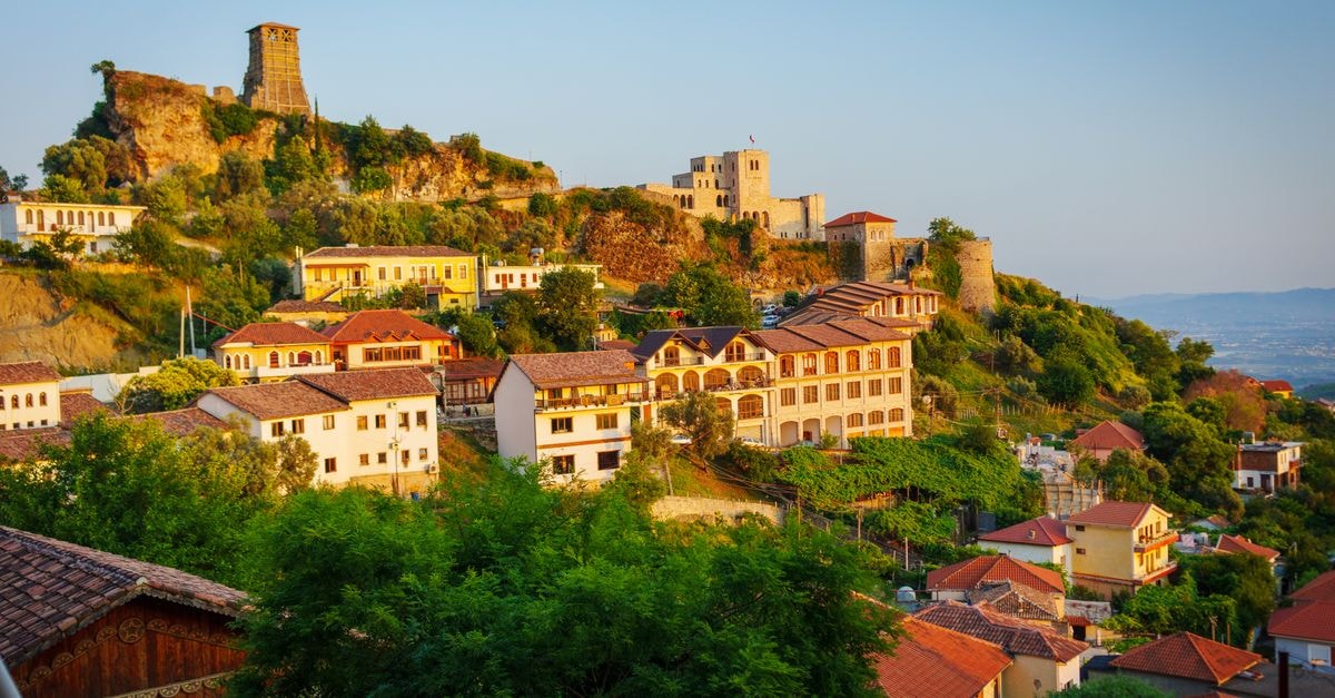 Charming view of Krujë Castle and old town in Albania with colorful houses at sunset.