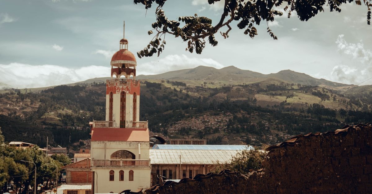 Majestic church tower in Huaraz, Peru against the Andes mountains backdrop under a cloudy sky.