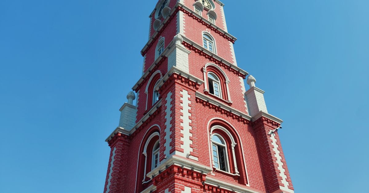 Karnal Travel Guide: Tradition, Taste, and Modern Comforts A stunning red brick tower reaches skyward beneath a clear blue sky, showcasing architectural elegance.