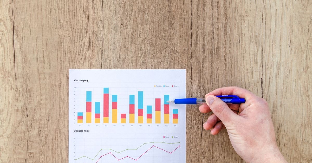 Micron narrows DRAM share gap with SK hynix to 1 point as Samsung retakes No. 1 in Q2 A hand points a pen at business graphs on a wooden table, highlighting data analysis.