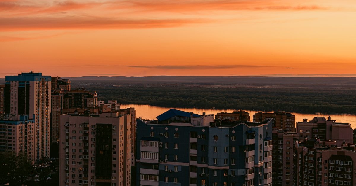 Ruma, Khabarovsk: Hotel on Pionerskaya Street Stunning sunset over a city skyline with river view, offering a vibrant urban landscape.
