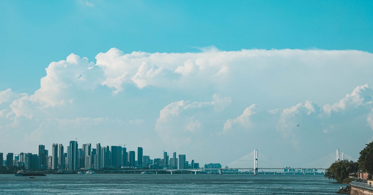 Xingzhou Hotel in Bazhong: Riverside Address on Jiangbei's Binhe Road Panoramic view of a city's skyline featuring a bridge and river beneath a stunning blue sky.