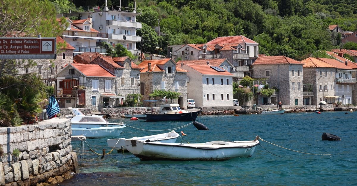 Picturesque coastal village with boats, stone houses, and lush greenery.