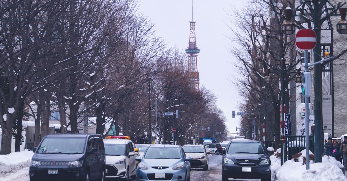 Sapporo travel guide: a calm, northern Japanese city worth slowing down for Winter scene in Sapporo, Japan. Snowy street with cars and Sapporo TV Tower.