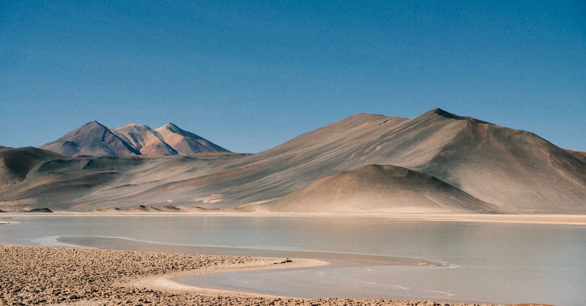 Explore the rugged beauty of the Antofagasta desert landscape with distant mountains under a clear blue sky.