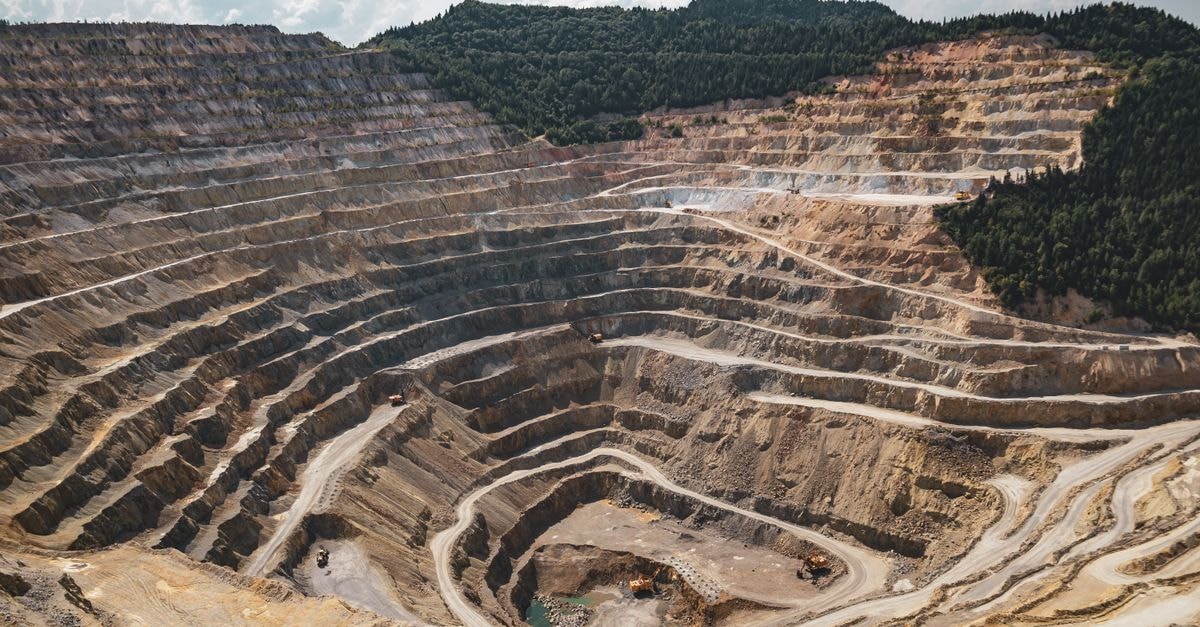 Coal India to open first overseas trading office in Singapore to pursue iron ore and critical minerals Aerial view of a large open-pit mine with terraced excavation during summer.