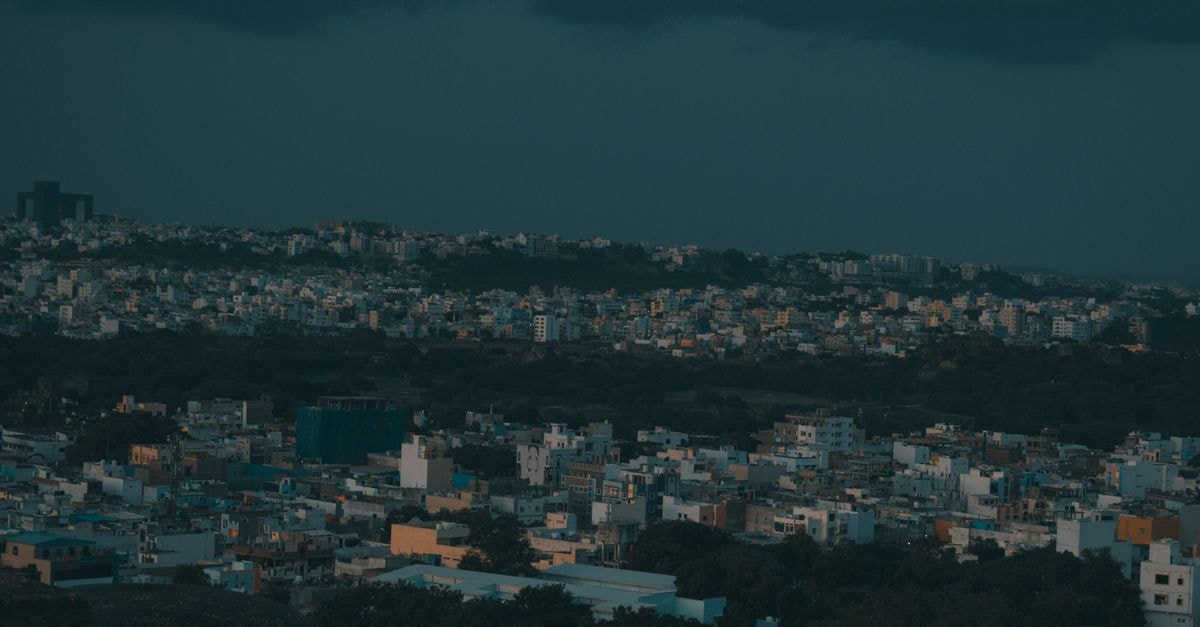 Aerial view of a dense cityscape captured at twilight, showcasing urban architecture under dramatic skies.