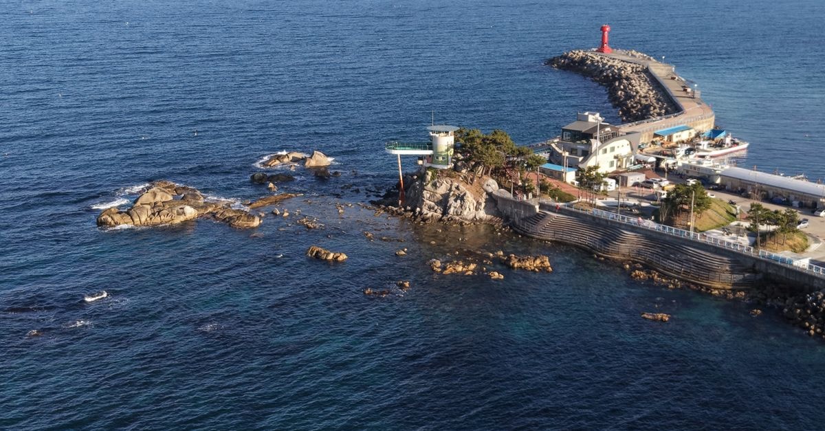 Kaesong Travel Guide: Culture, History, and Food Context Aerial image of Sokcho Lighthouse on the rocky shore of South Korea during daytime.