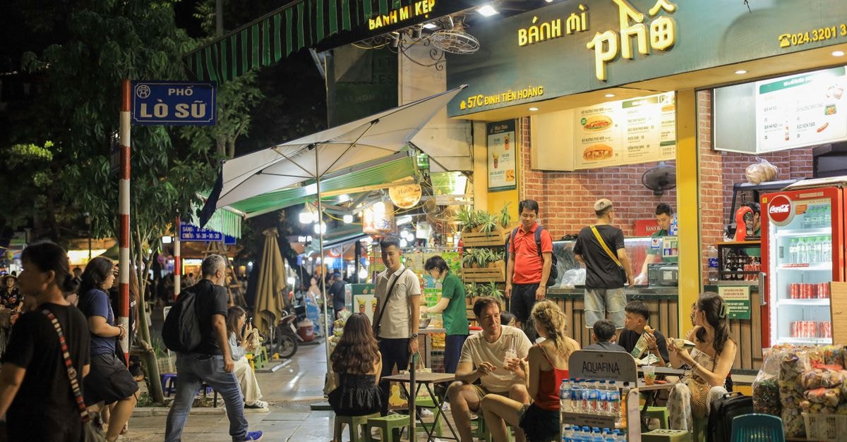 Slow Days in Thai Nguyen: A Vietnam Travel Guide for Curious Foodies Vibrant night scene of people enjoying street food outside a Vietnamese sandwich shop in Hanoi.